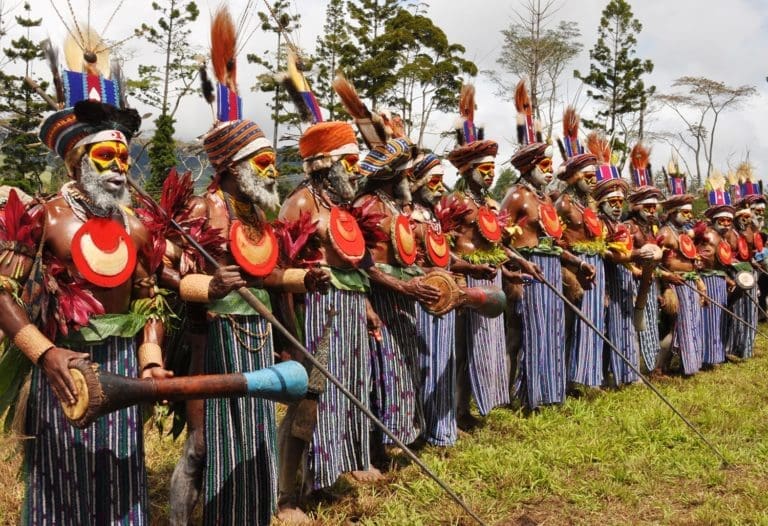 A tribal grup at the SingSing Festival, wearing blue and white sarongs and red discs on their chests, PNG
