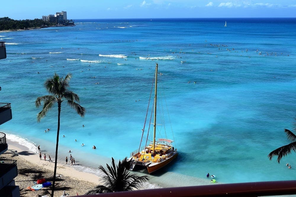 The view of Waikiki Bay, surfers and  a moored catamaran from my hotel room, Honolulu, 