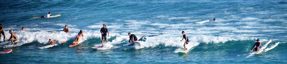 A row of surfers on a wave, Waikiki Beach, Honolulu
