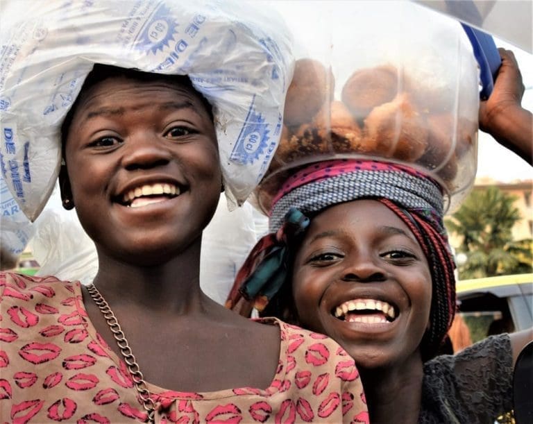 A portrait of two smiling girls selling goods on the roadside DRC