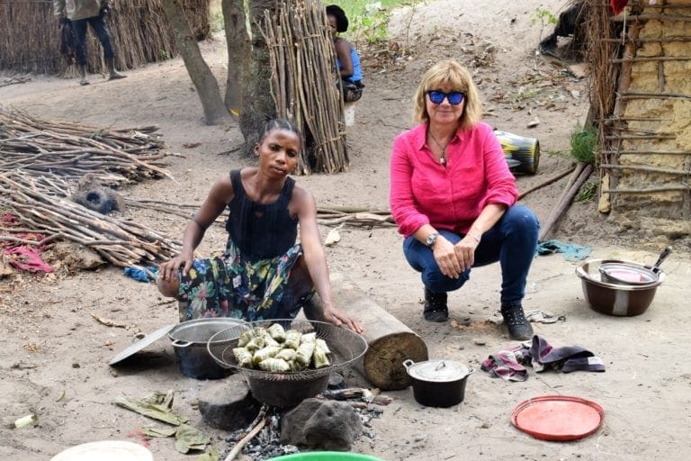 Sue with a villager cooking lunch on an open fire, DRC