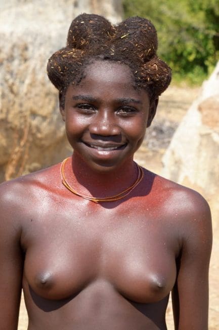 Young bare breasted Mucubal woman with shaped mud covered hairstyle