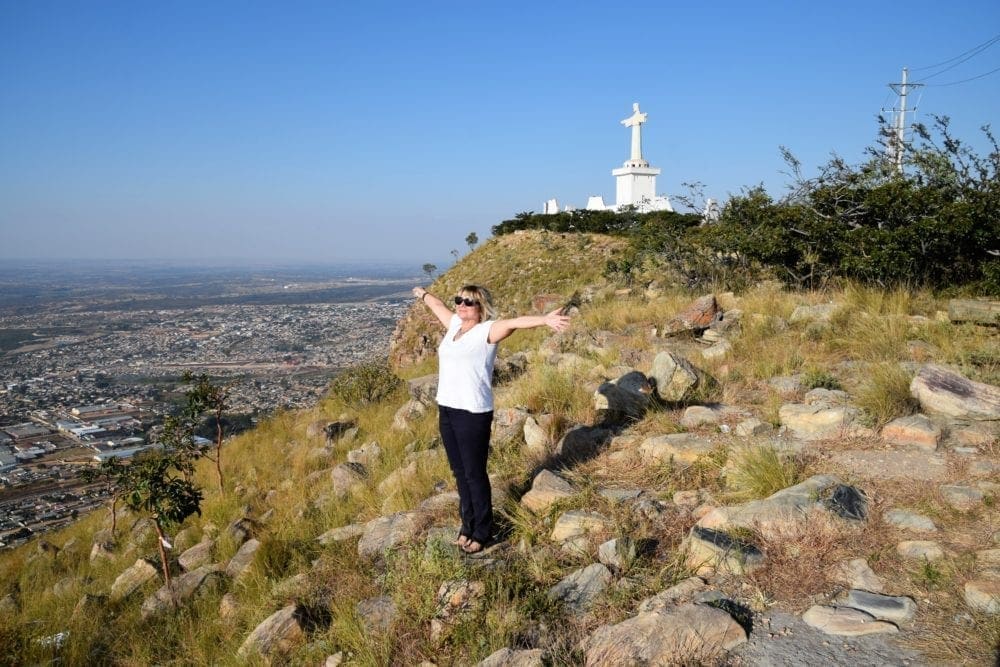 Sue with arms outstretched by the Redeemer statue on the escarpment above Lubango